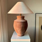 Devon earth tone ceramic table lamp with off-white linen lampshade on a white pedestal